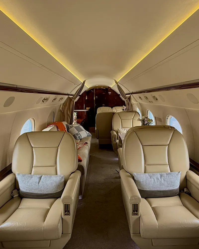 Two cream leather seats facing forward along the aisle of a large jet cabin