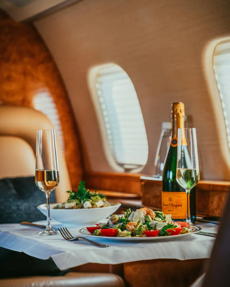 Champagne and a light lunch on a white tablecloth beside a cabin window