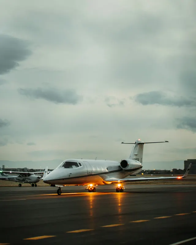 Business jet taxiing under a gray evening sky with its lights on