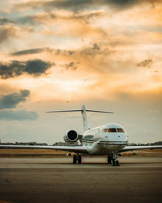 Business jet parked on the ramp under a golden sunset sky