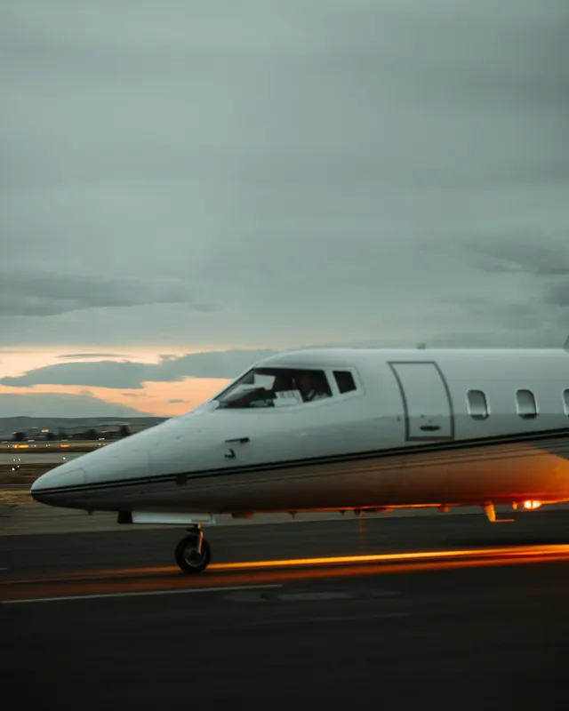 Nose and cockpit windows of a small business jet on a taxiway at dusk