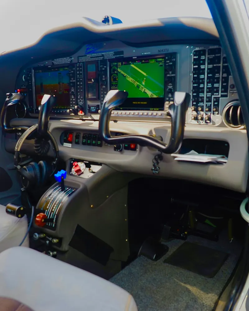 Flight deck with glass displays and control yokes, seen from the cabin door