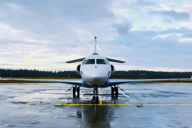Business jet on a wet ramp with pine trees behind
